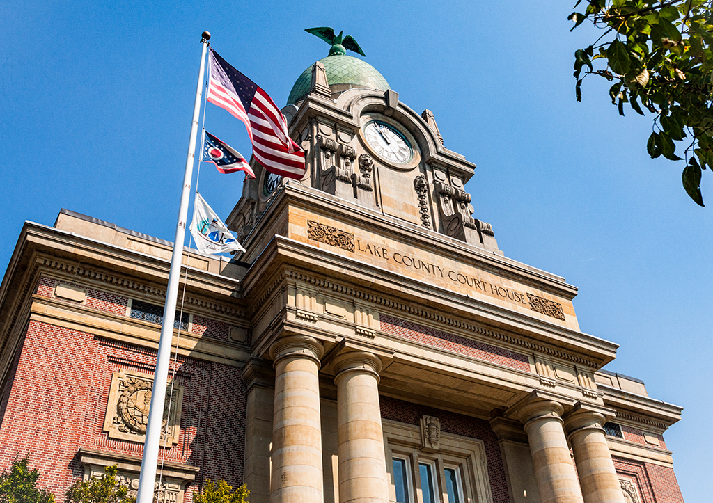 Photo of a classic government building featuring bricks, columns, and friezes, a clock tower with a domed copper roof at the top.